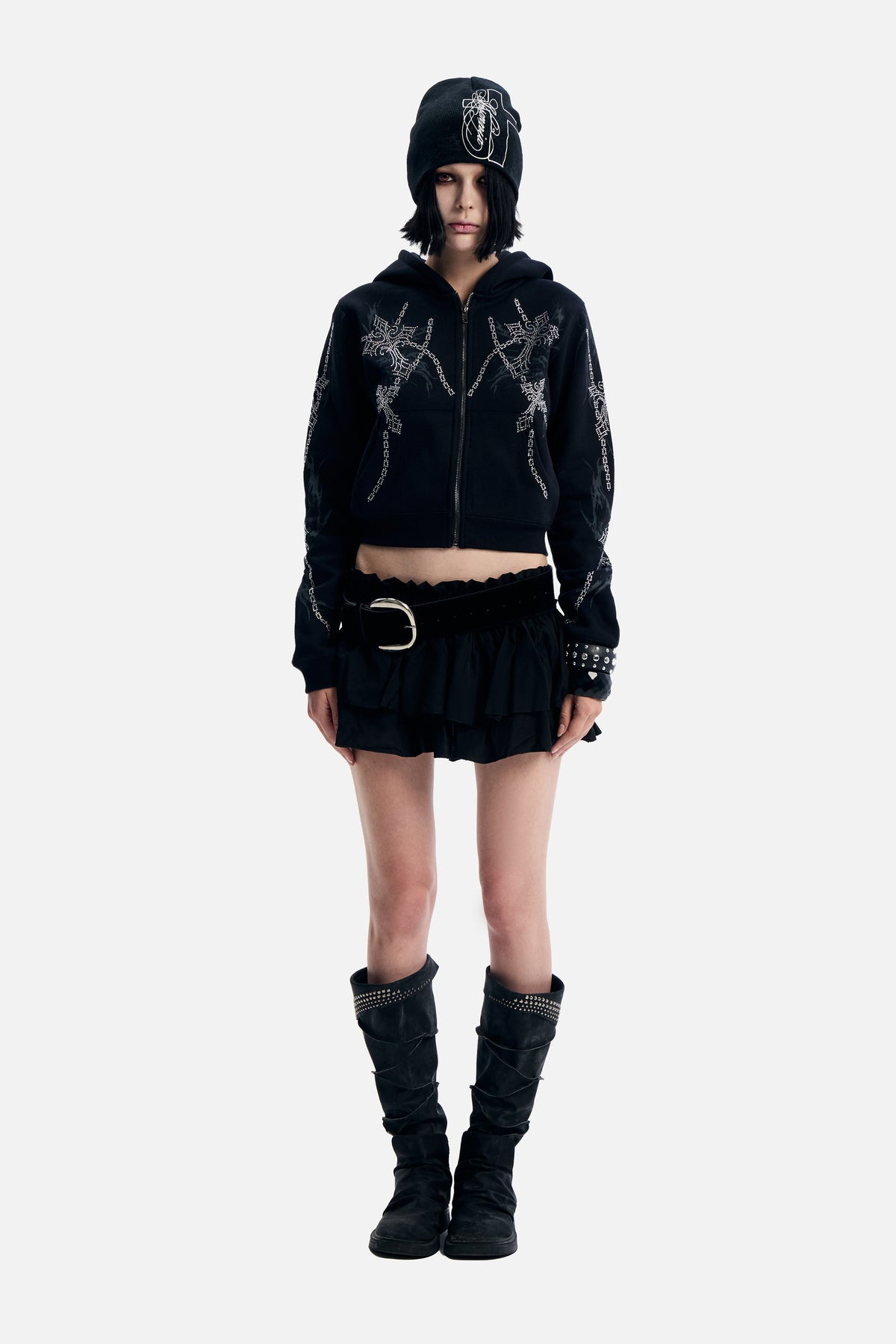 Model wearing the black Chain Rhinestone Hoodie cropped zip up with a ruffle mini skirt and boots, full length