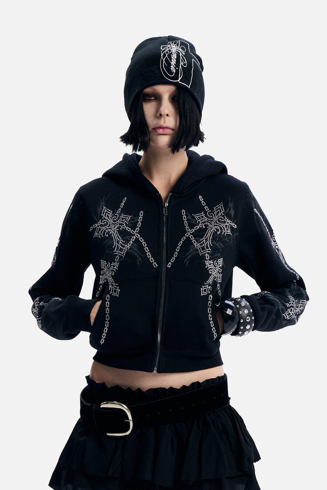 Model with hands in pockets wearing the Chain Rhinestone Hoodie and studded cuffs