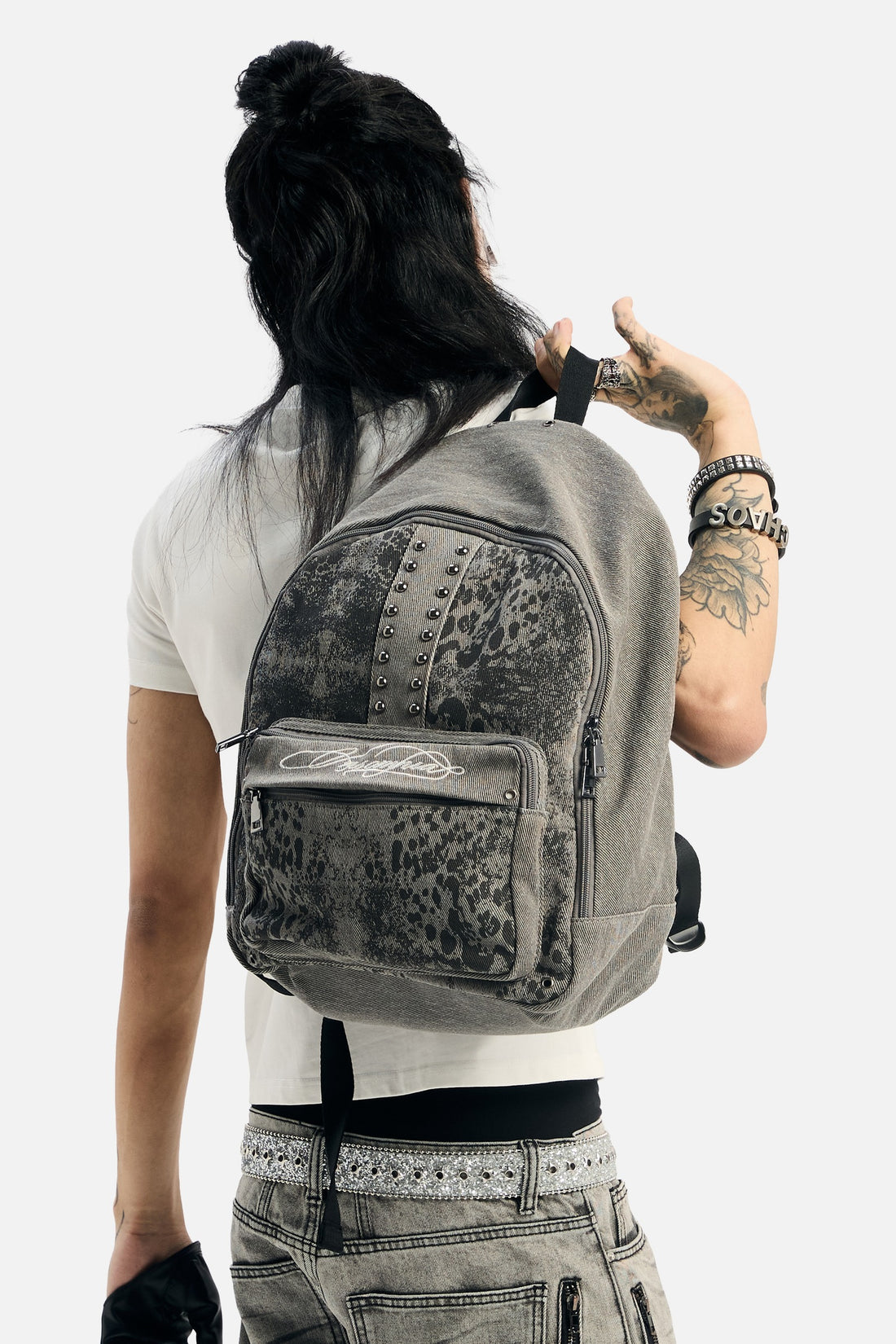 Back view of a model carrying the Denim Cheetah Backpack over a white tee