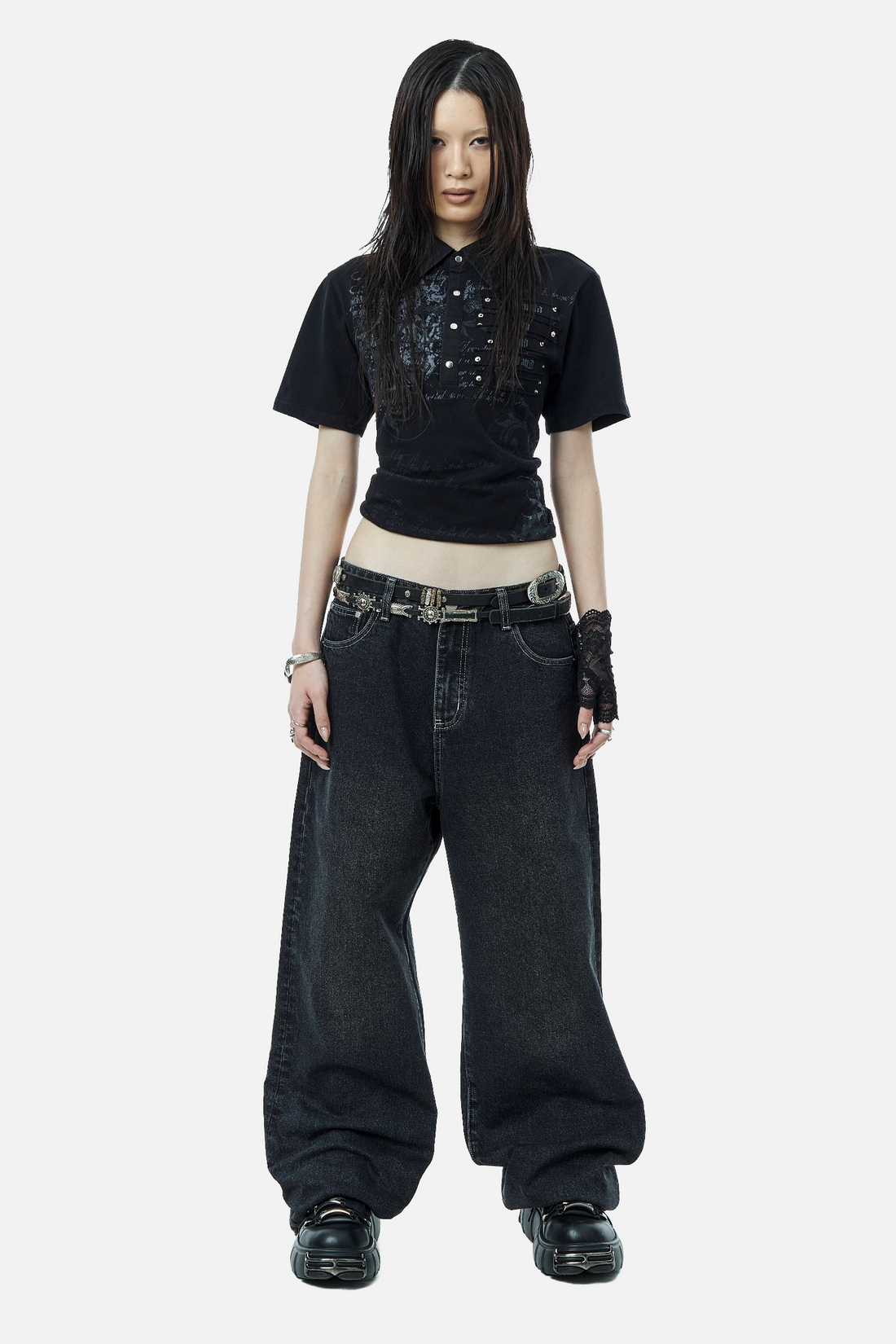 Full-length front view of the Black Thorns Polo cropped over wide dark baggy jeans