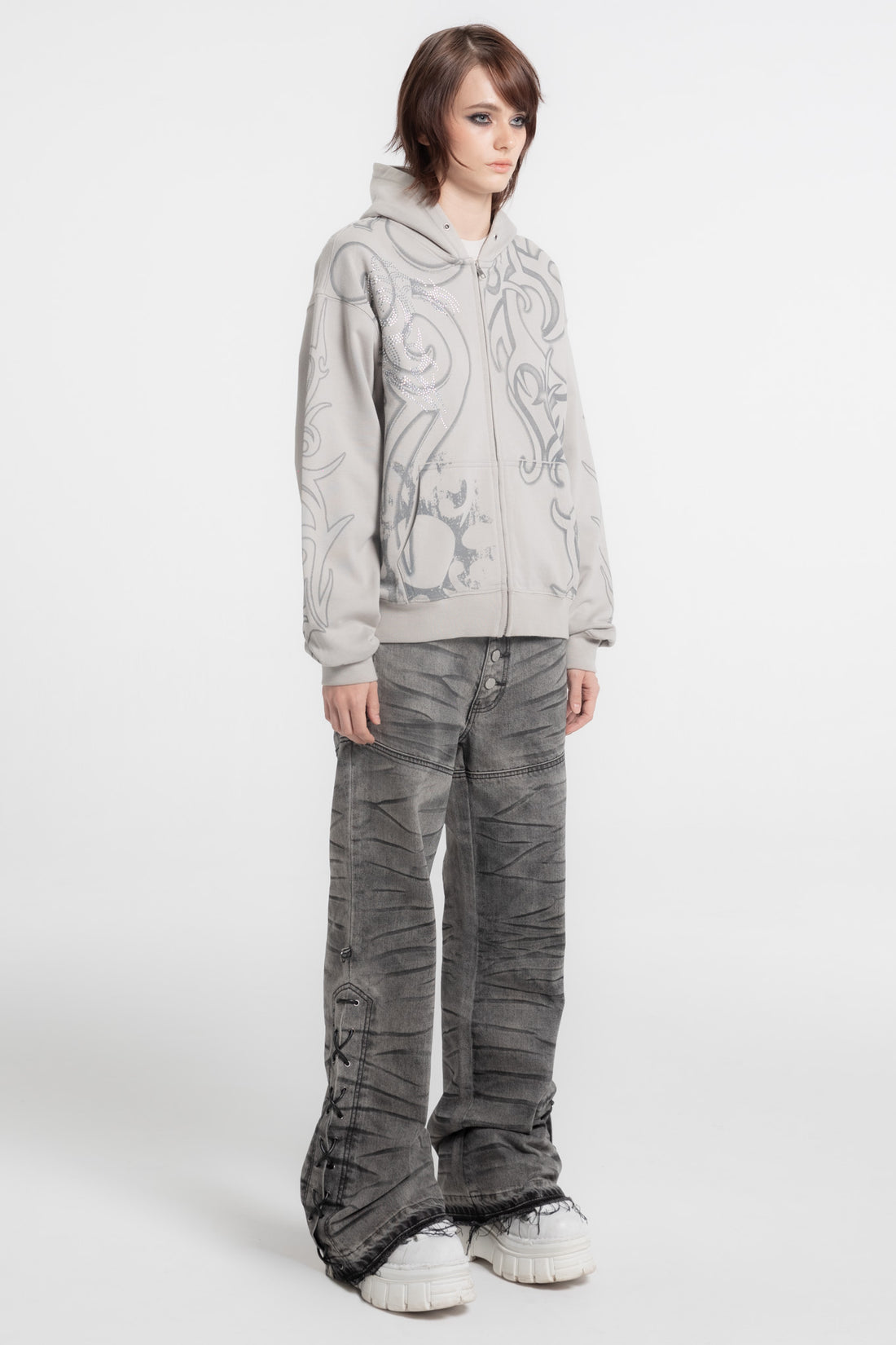 Model in the Rhinestone Tribal Zip Hoodie with gray wide jeans and white sneakers, side view