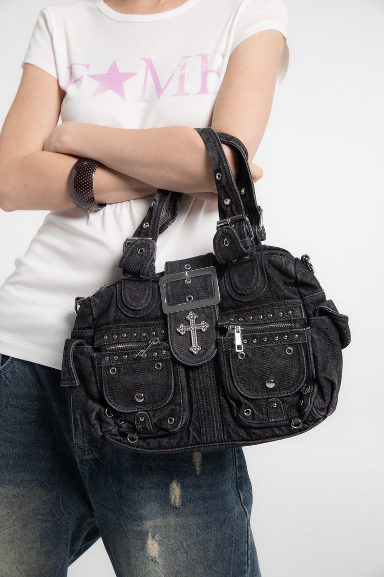 Cropped view of the Cross Denim Shoulder Bag on an arm, showing cross buckle and studs