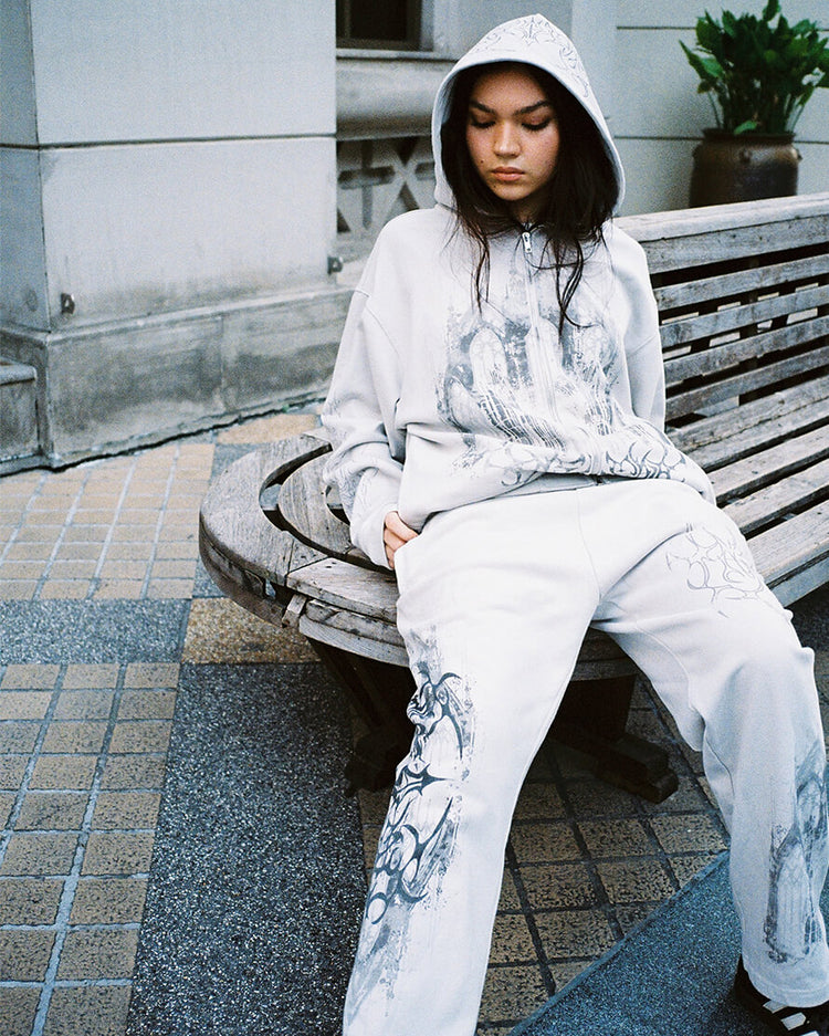 Model sitting on a bench in the Gray Cathedral Sweatpants and matching hooded sweatshirt