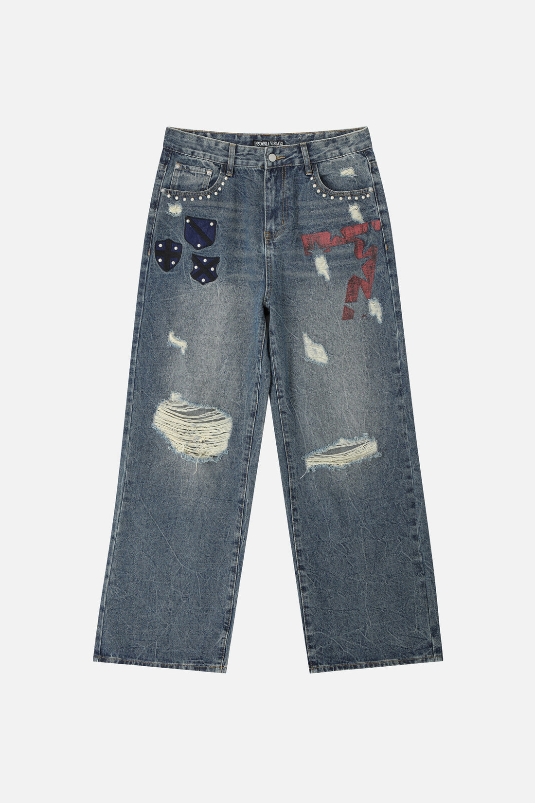 Front of the Patch Outlaw Denim laid flat, faded blue with studded patches and ripped knees