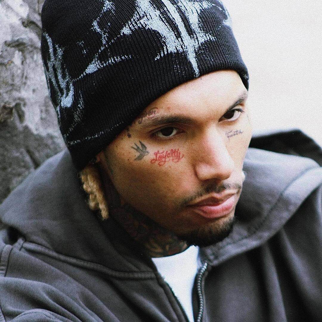 Close portrait of a tattooed model in the Glitch Logo Beanie and grey zip hoodie