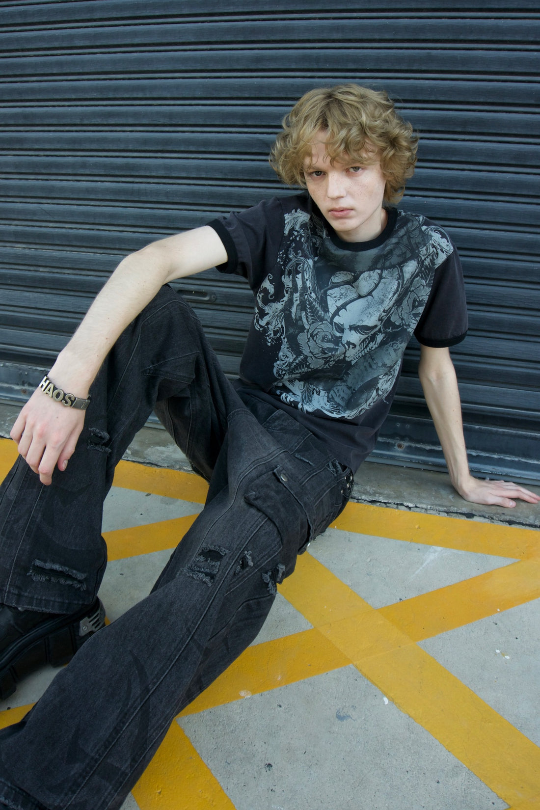 Thorns Ringer Tee with Tribal Destroyer Denim, model sitting by a metal shutter