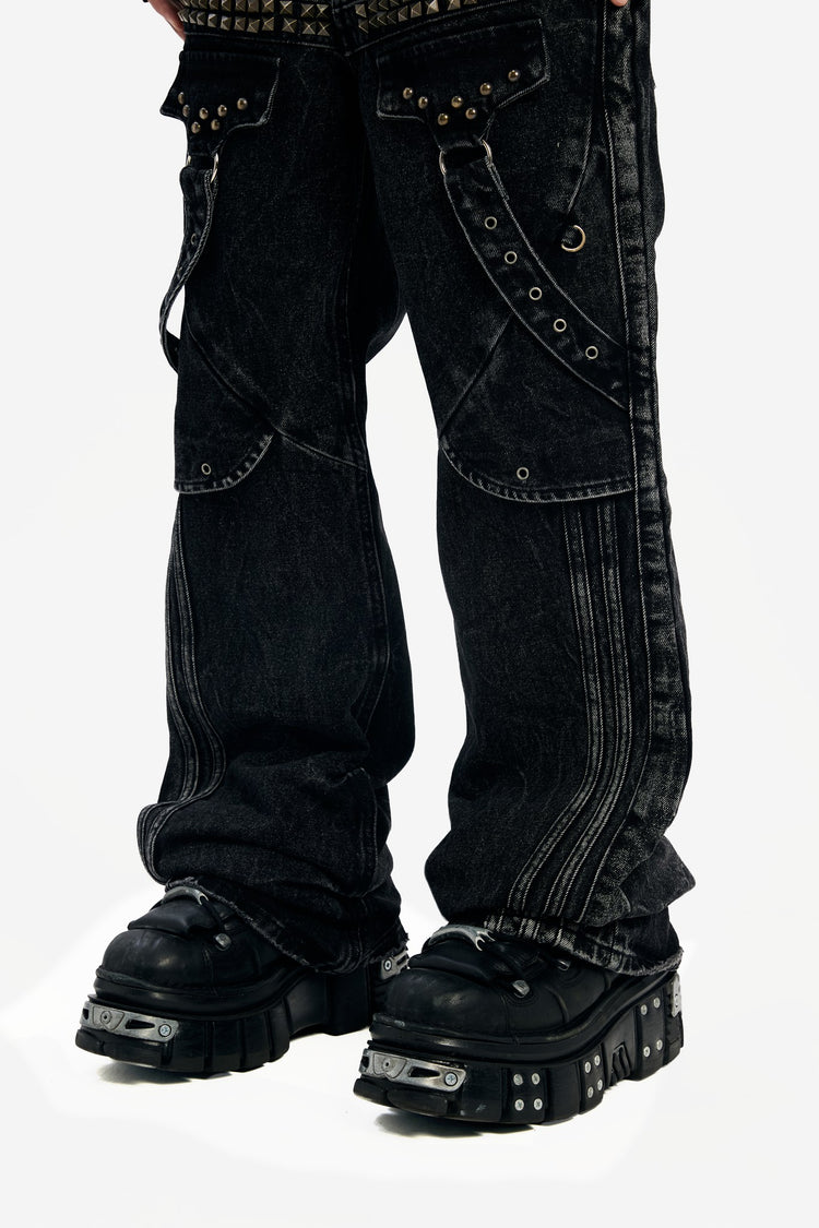 Close-up of the Studded Rogue Denim legs showing zip panels, studded straps and flared hems
