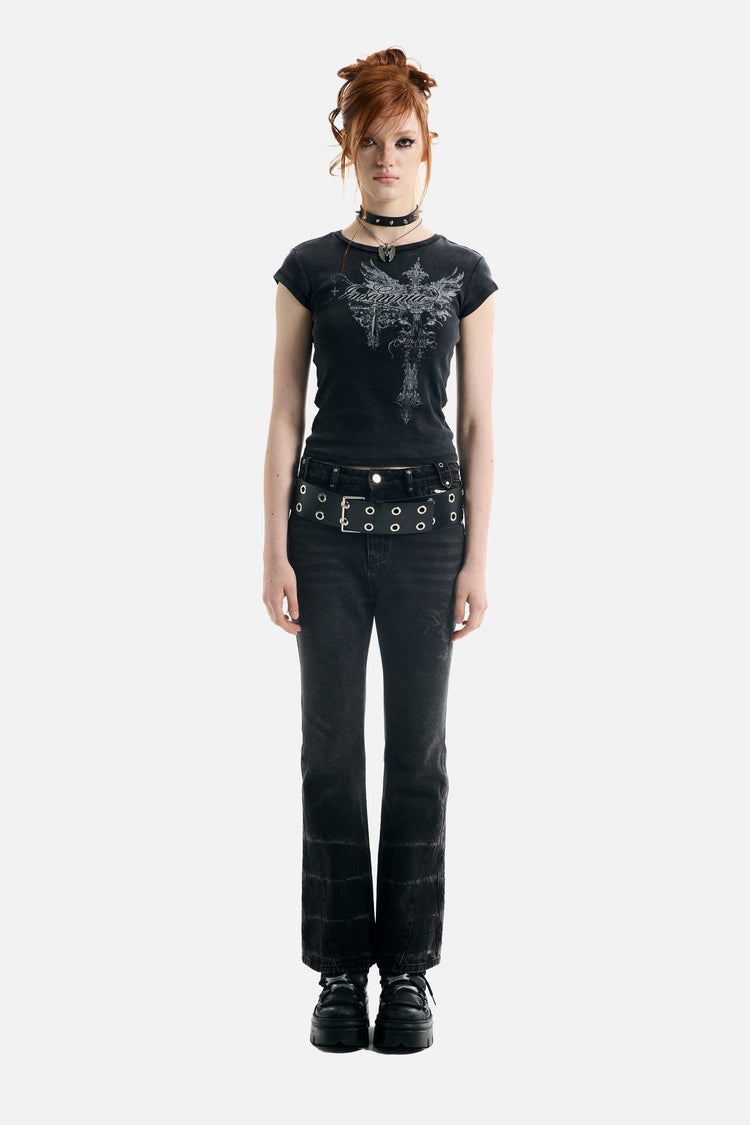 Model in the black Treasure Tee with black flared jeans and platform boots, full-length