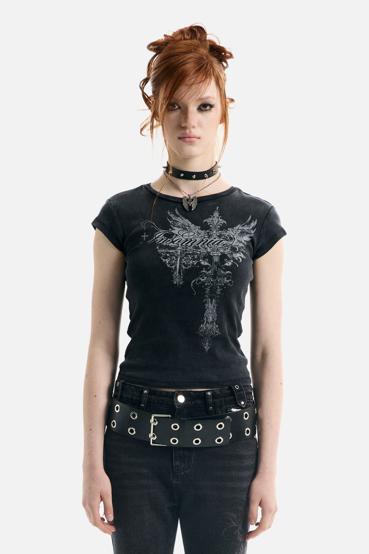 Model in the black Treasure Tee with silver winged cross graphic and grommet belt