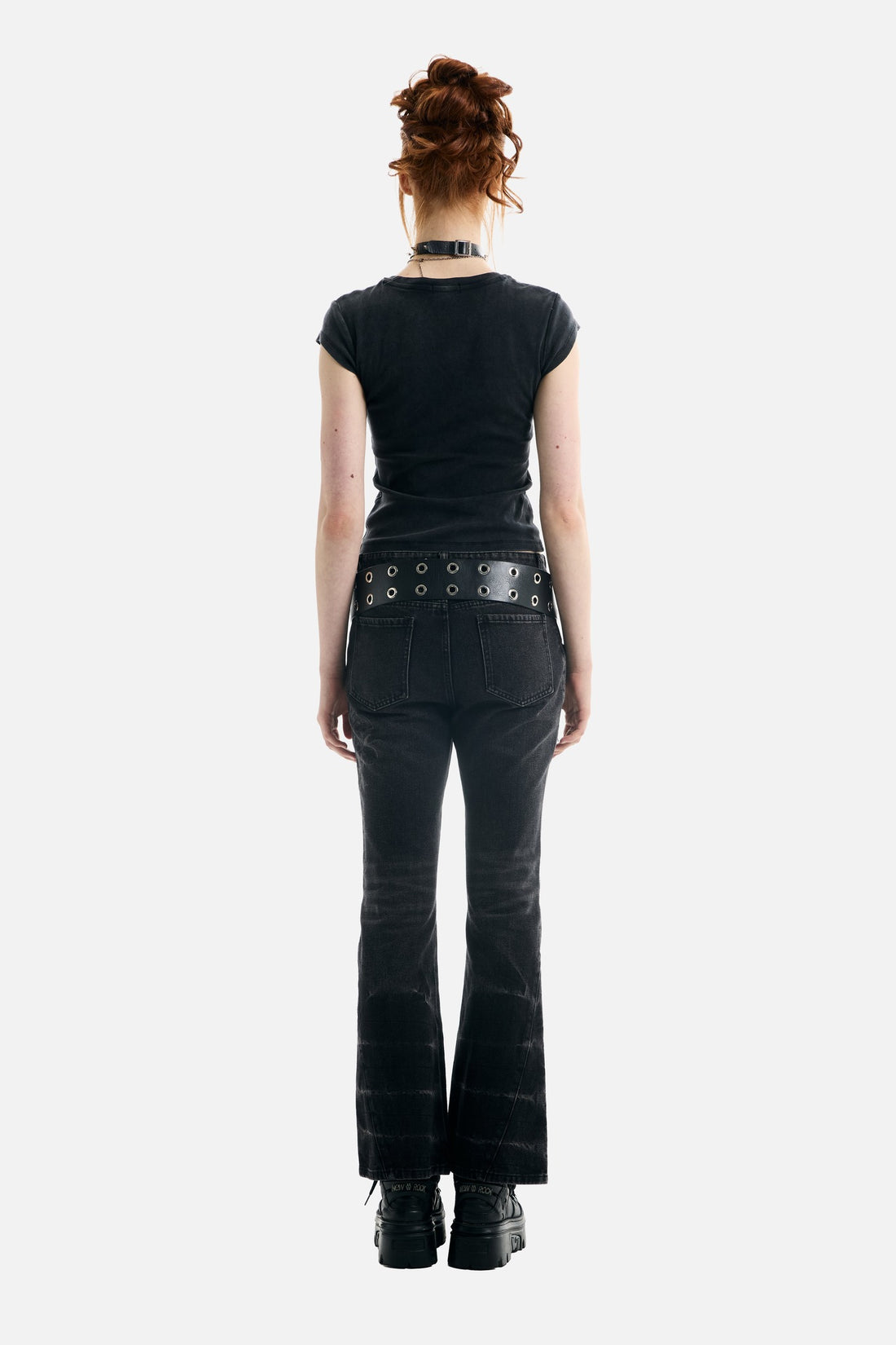 Back view of the black Treasure Tee with grommet belt and flared jeans, full-length