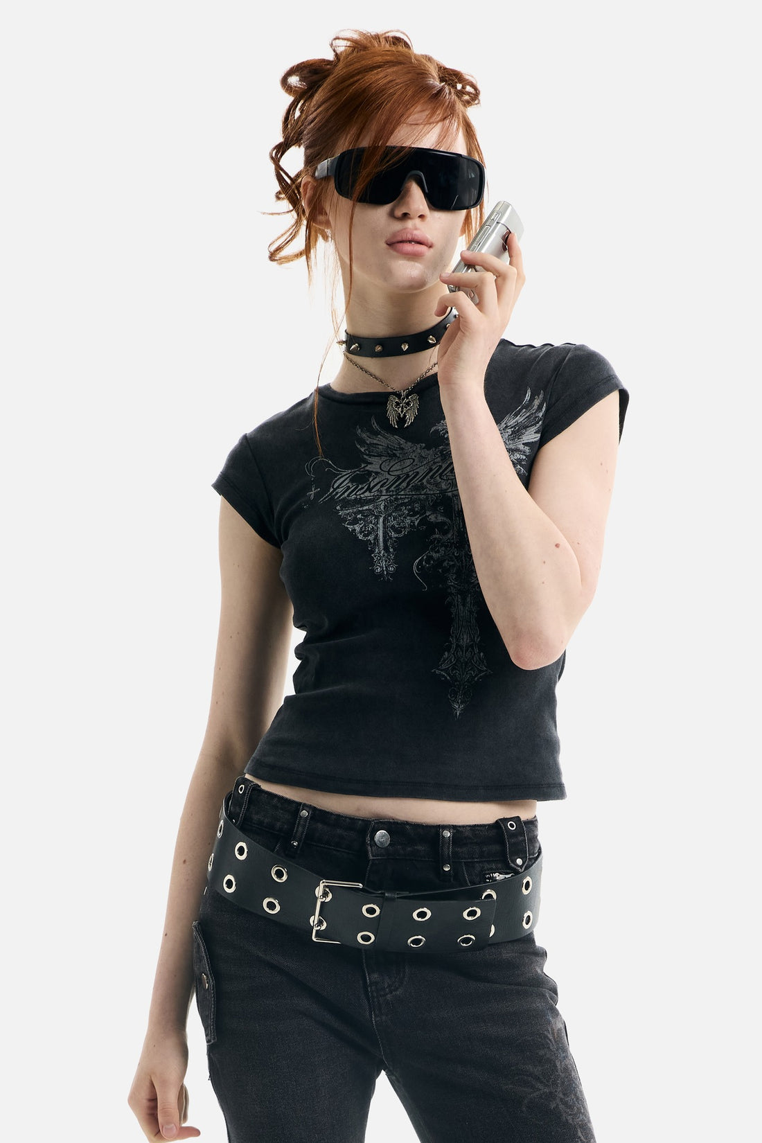 Model in sunglasses holding a phone, wearing the cropped black Treasure Tee