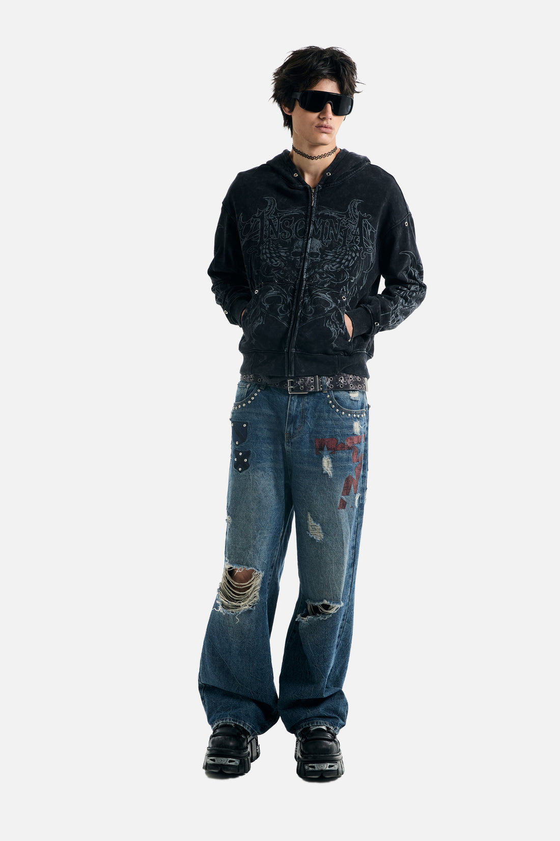 Full-length front view of the Tribal Zip Up Hoodie with hands in pockets and ripped jeans
