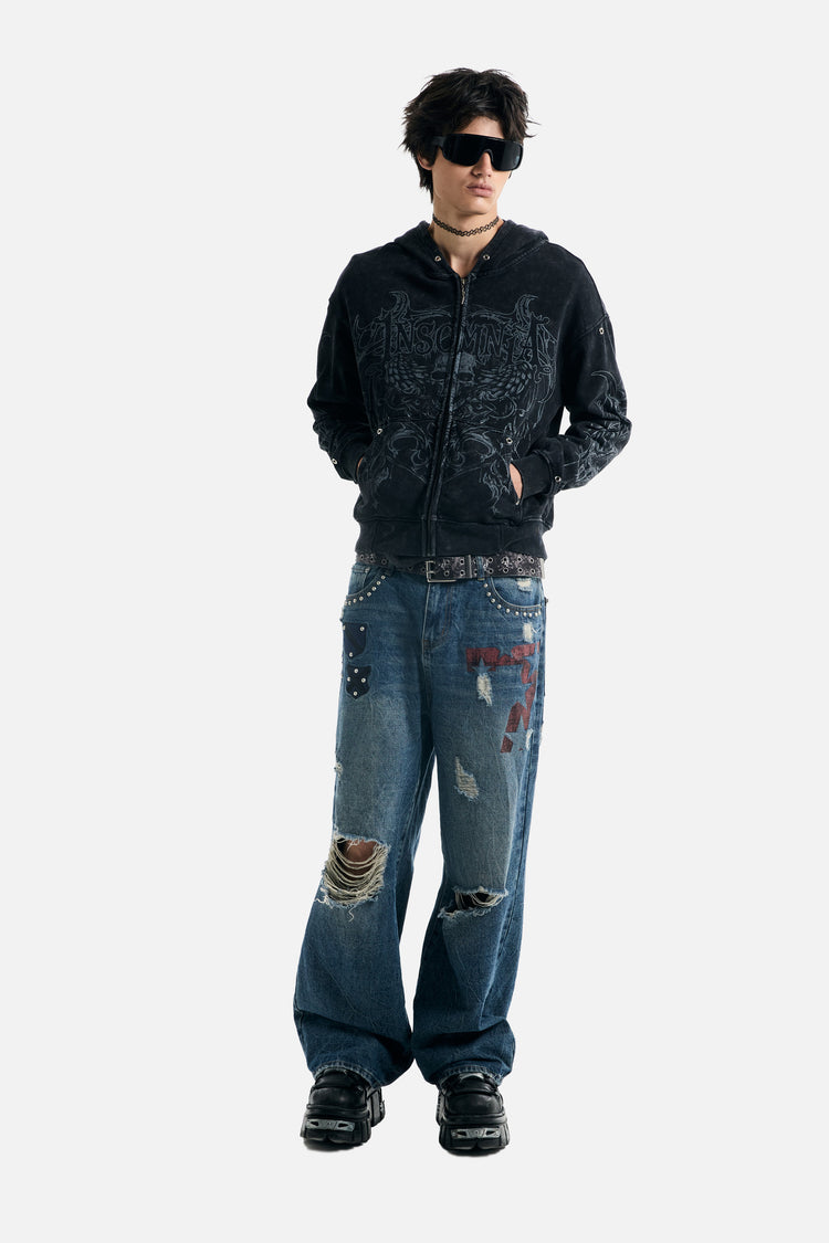 Full-length front view of the Tribal Zip Up Hoodie with hands in pockets and ripped jeans