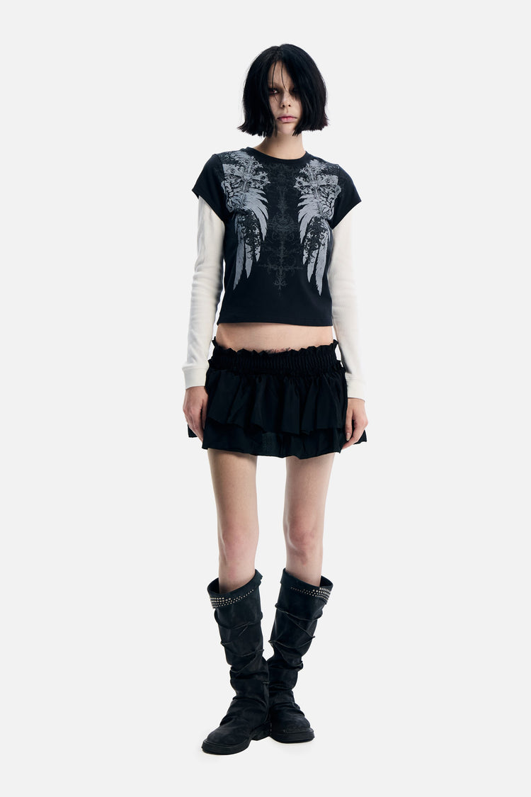 Model wearing the black Wings 2fer Womens Long Sleeve with white layered sleeves and a ruffle mini skirt, full length